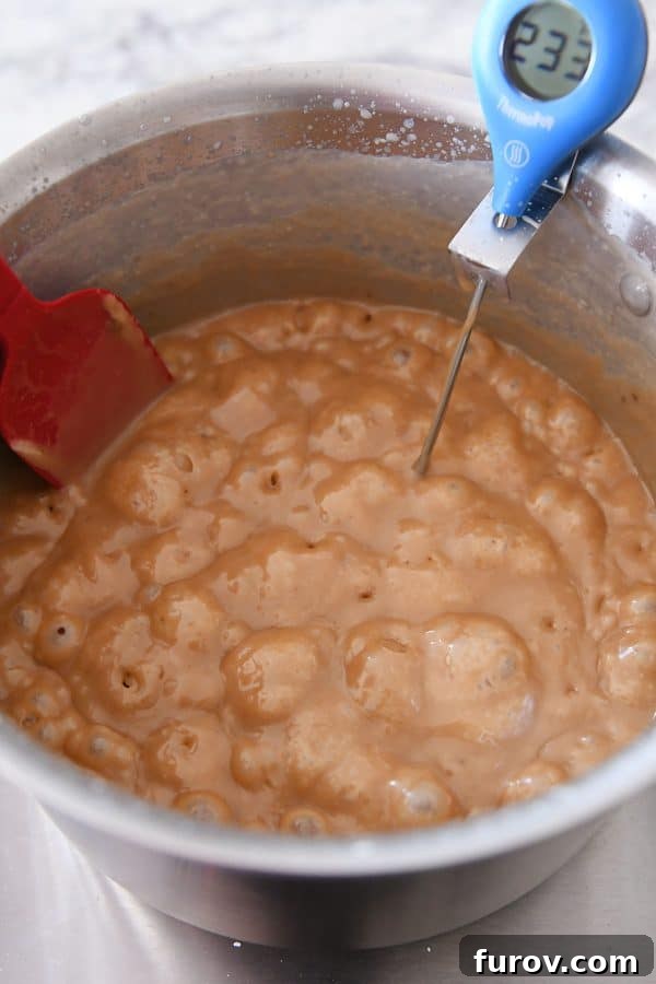 Caramels cooking to 245 degrees in a metal pot, achieving a rich, golden hue and perfect consistency.