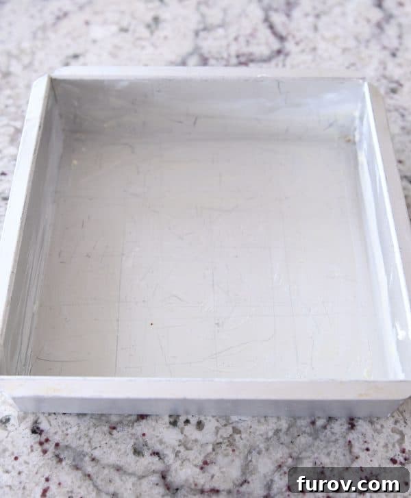 An 8x8-inch square pan, meticulously buttered and ready for a batch of homemade caramels.