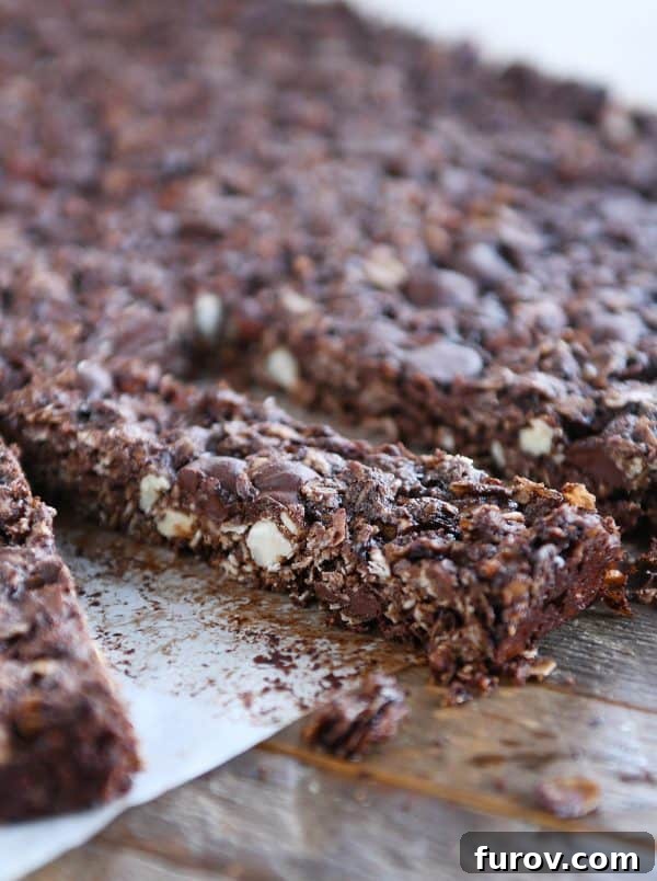 Granola bars being cut into thin, rectangular pieces on a baking sheet, showcasing their uniformity.