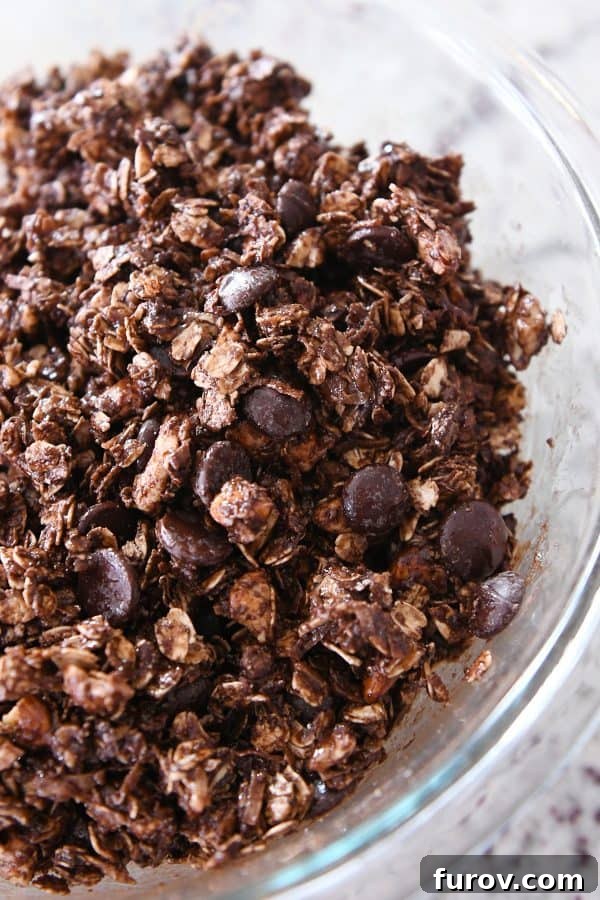 Chocolate chips mixed into the granola and syrup mixture, ready for pressing into a pan.