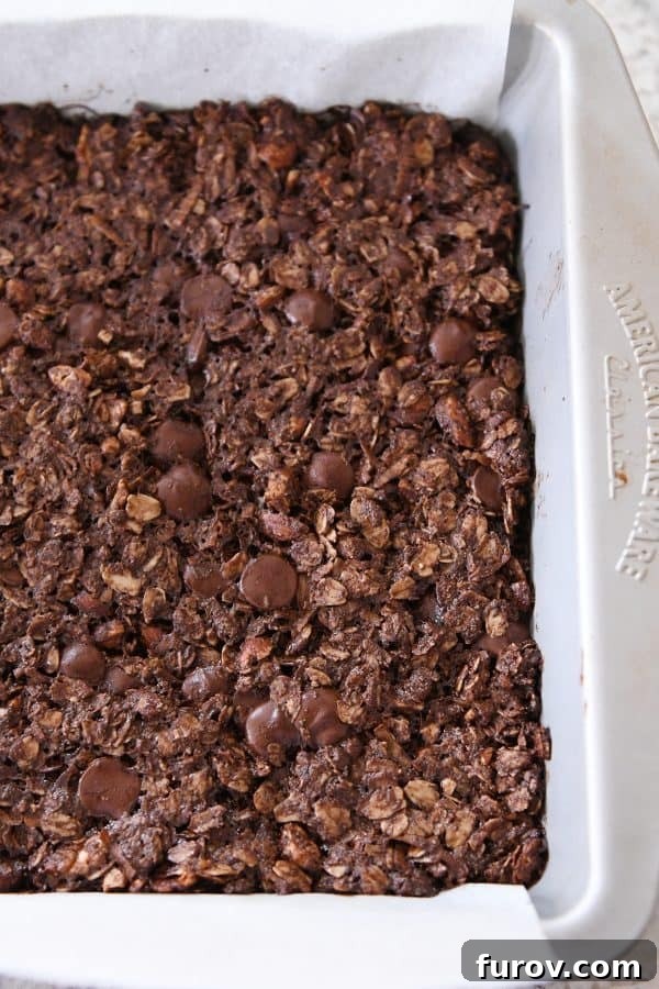 A full pan of baked dark chocolate brownie granola bars, golden brown and ready to cool.