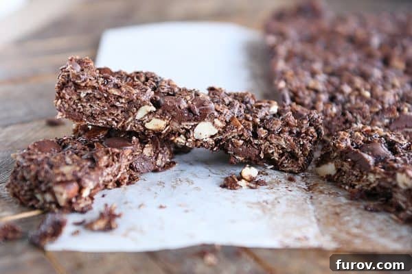 A single dark chocolate brownie granola bar resting on parchment paper, showcasing its texture.