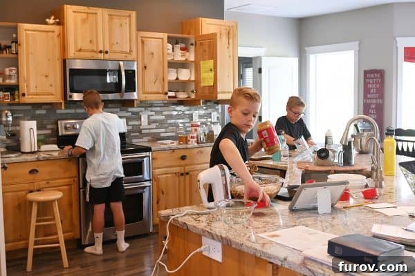 Two children happily working together in a kitchen, preparing food.