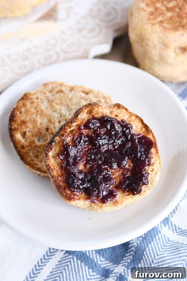 Simple Homemade English Muffins No Mixer Whole Grain 2 Split open easy homemade english muffin with butter and jam on white plate.