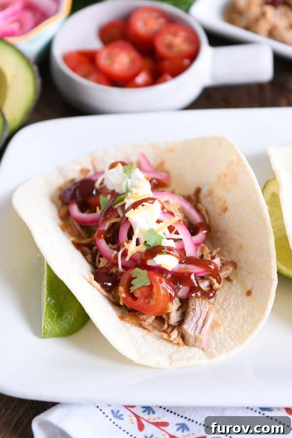 Ultimate Instant Pot BBQ Pork Tacos 2 A delectable Instant Pot BBQ pork taco, generously topped with vibrant pickled onions and drizzled with a rich barbecue sauce, ready to be enjoyed.