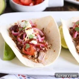 A delicious Instant Pot BBQ pork taco, adorned with pickled onions and a luscious BBQ sauce drizzle.
