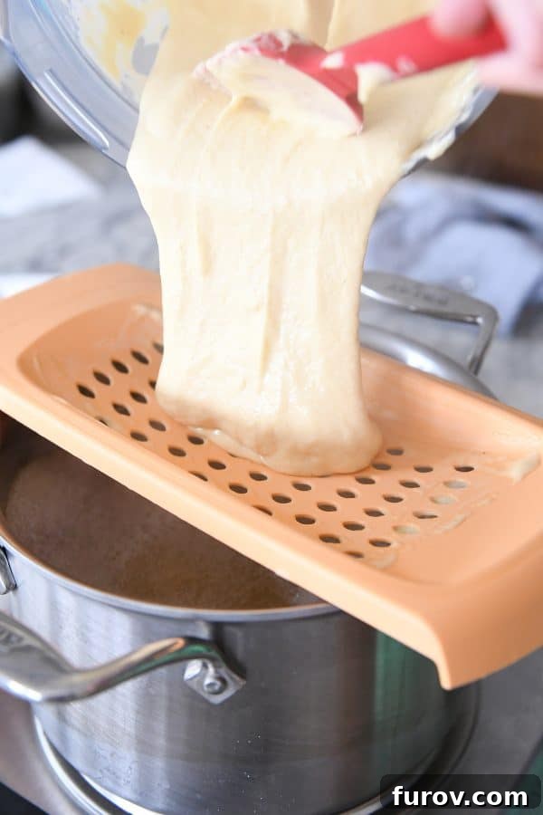Whip Up Perfect German Spaetzle Quick Video Guide 7 Pouring spaetzle batter onto spaetzle maker over pan of hot broth.