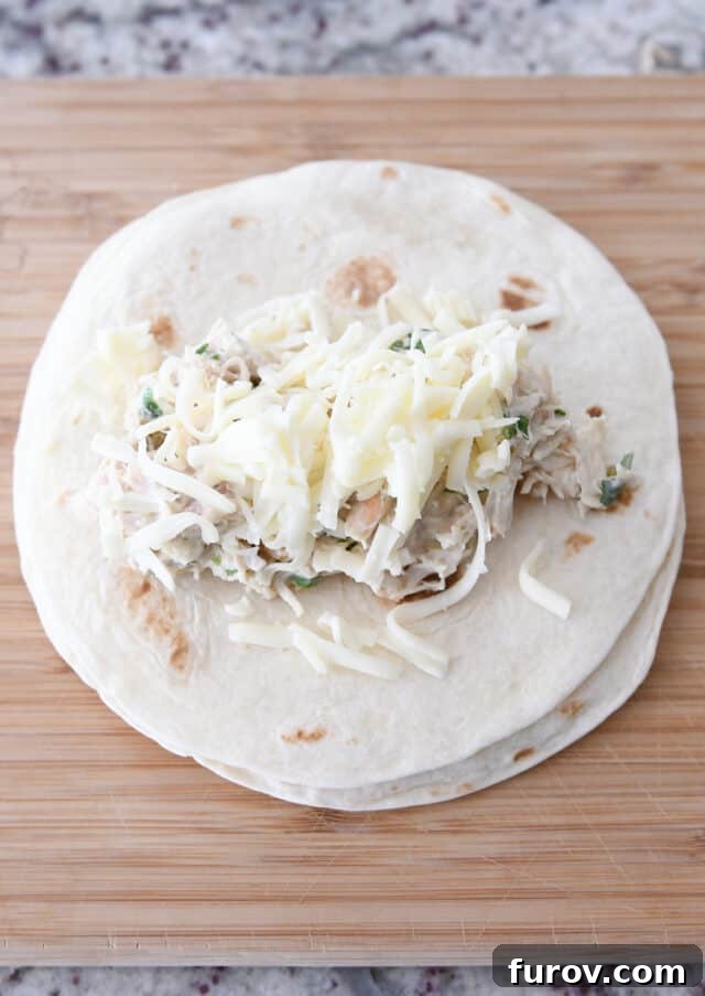8-inch tortilla with enchilada filing and cheese on wood cutting board.