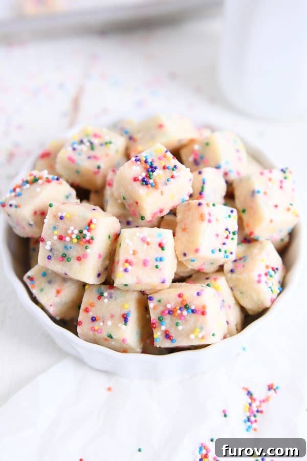 Top down view of baked funfetti shortbread bites in white bowl, highlighting their vibrant colors and perfect texture.