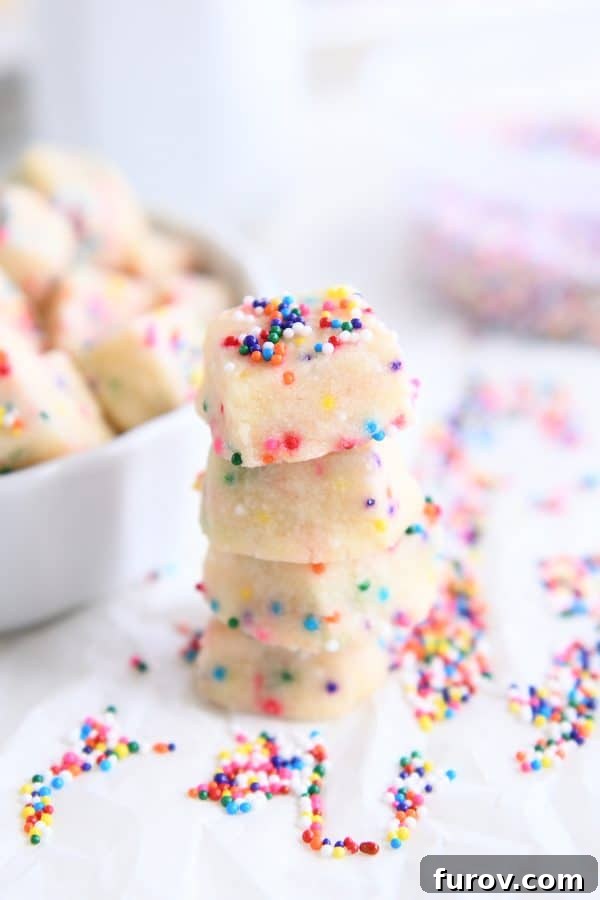 A perfectly stacked pile of freshly baked funfetti shortbread bites, displaying their delicate texture and sprinkle-dotted surface.