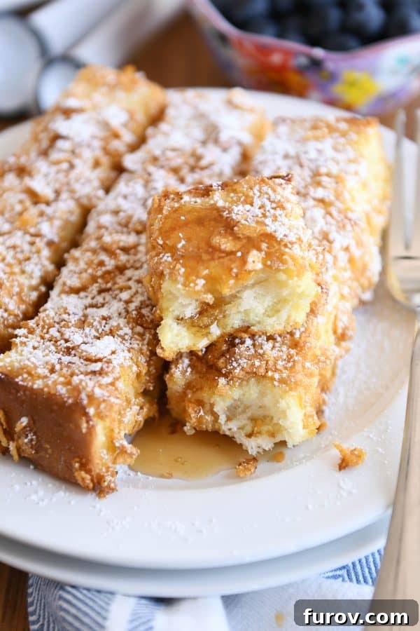 Crunchy baked french toast sticks with powdered sugar and syrup.