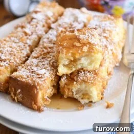 crunchy baked french toast sticks on white plate with powdered sugar and syrup