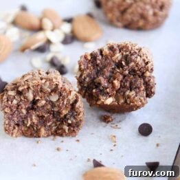 Close-up of a broken chocolate peanut butter granola bite, showing the rich texture and mini chocolate chips inside.