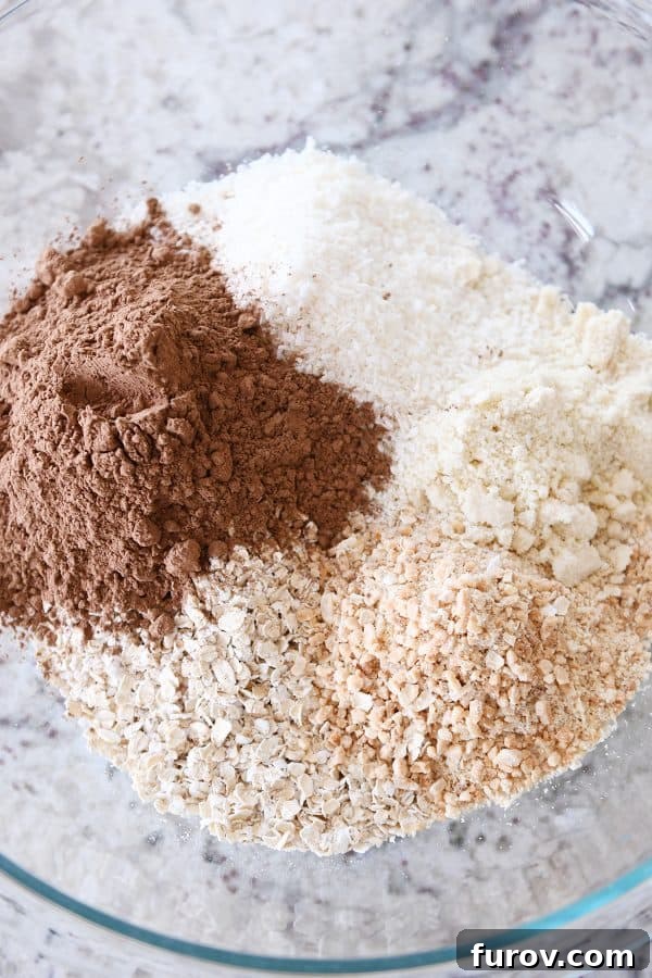 Close-up view of the dry ingredients for chocolate peanut butter granola bites, beautifully mixed in a clear glass bowl, showcasing texture and color.