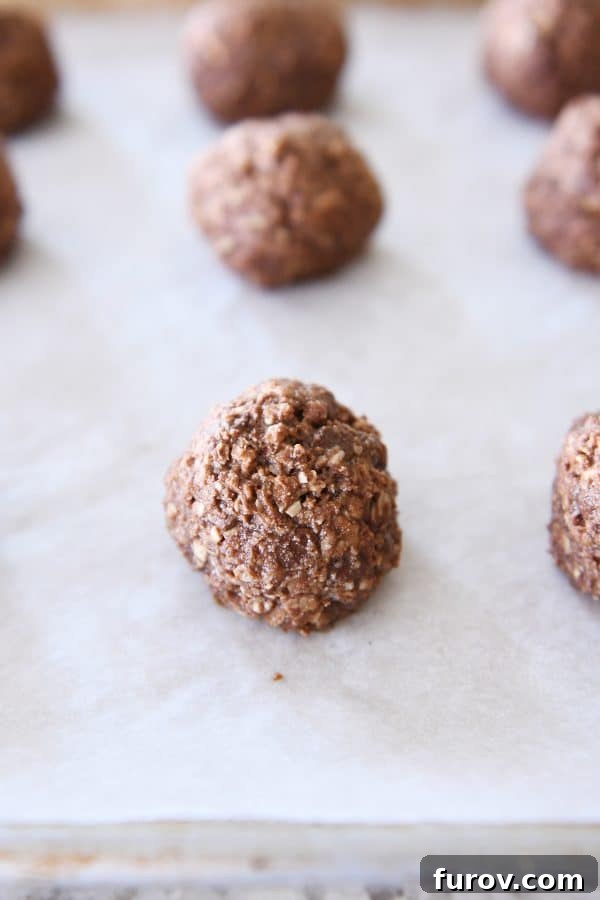 A single baked chocolate peanut butter granola bite resting on a parchment-lined sheet pan, showcasing its perfectly golden and set exterior.