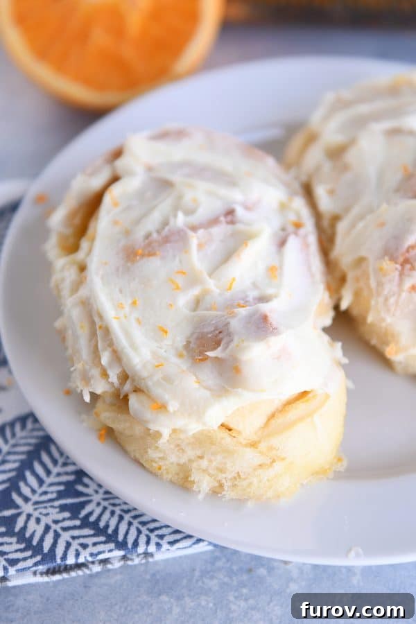 Perfected Homemade Orange Sweet Rolls 15 A single, delectable homemade orange sweet roll resting on a pristine white plate, showcasing its fluffy texture and glaze.
