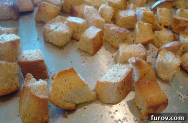 Perfectly baked, golden-brown bread cubes resting on a metal cookie sheet, illustrating the ideal crispness of homemade croutons.