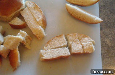 Bread strips being expertly cut into small, even cubes on a white cutting board, transforming them into the foundational pieces for delicious croutons.