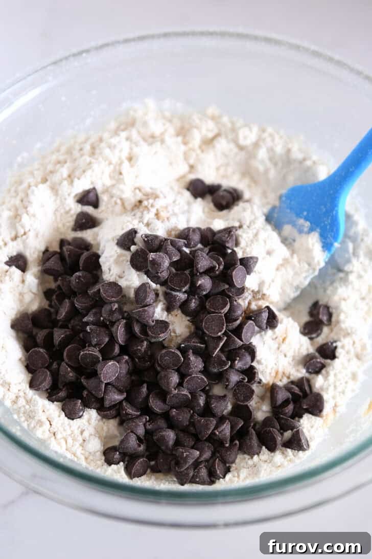 A glass bowl containing flour and a generous amount of chocolate chips.