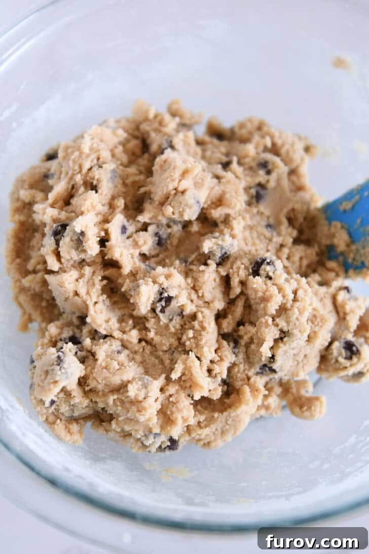 Top-down view of a glass bowl filled with rich chocolate chip cookie dough.