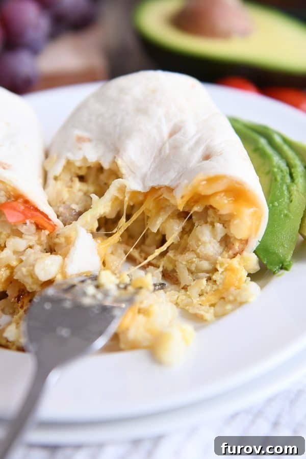 Stringy cheese pulling away on easy freezer breakfast burritos on white plate.