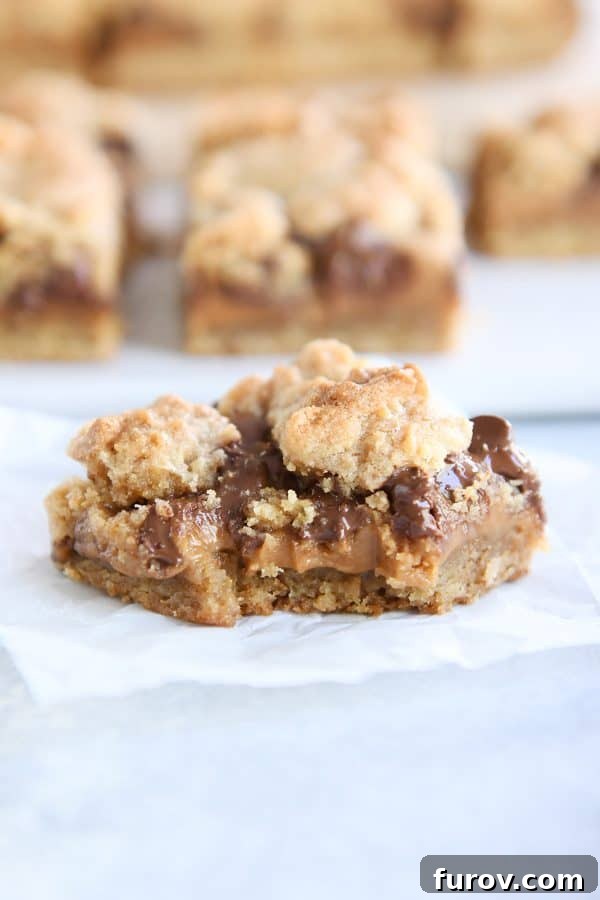 Smores Inspired Caramel Peanut Butter Cookie Bars 2 A delicious caramel peanut butter cookie bar with a bite taken out, revealing gooey layers.