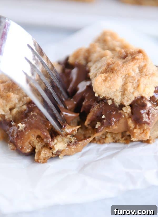 Smores Inspired Caramel Peanut Butter Cookie Bars 3 A fork taking a bite out of a warm caramel peanut butter cookie bar, showing its soft interior.