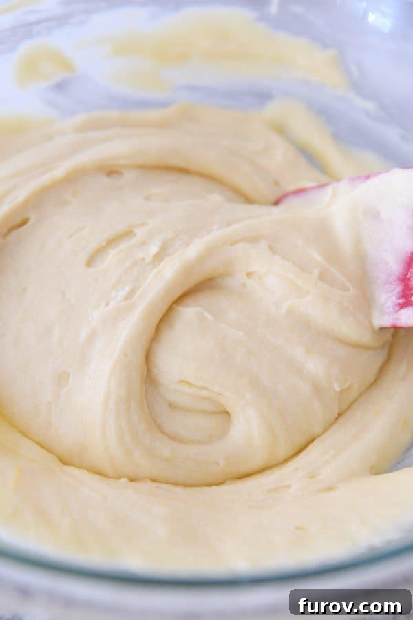 Tangy Rhubarb Custard Delight 6 A smooth, light-colored cake batter, resembling soft vanilla cream, swirled in a clear glass mixing bowl, awaiting the addition of rhubarb.