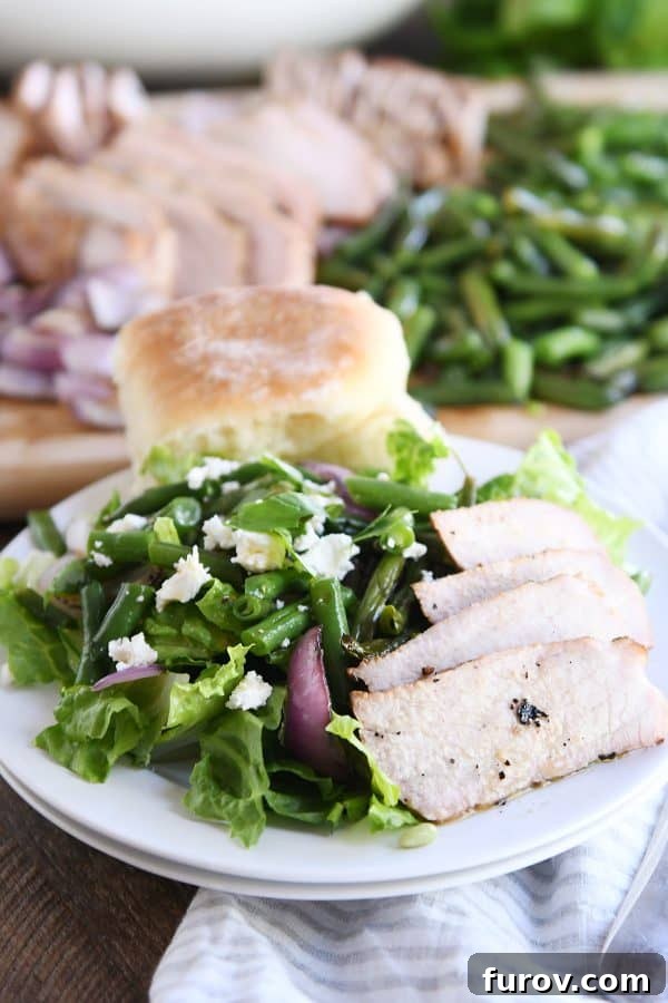 Sliced grilled pork and fresh vegetables arranged attractively on a white plate, ready to be served as a salad.