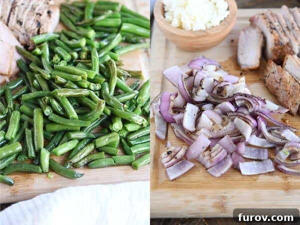 Chopped grilled green beans and grilled onions neatly arranged on a bamboo cutting board, ready for the salad.