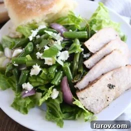 Grilled pork salad with pork, red onions, green beans and roll on white plate