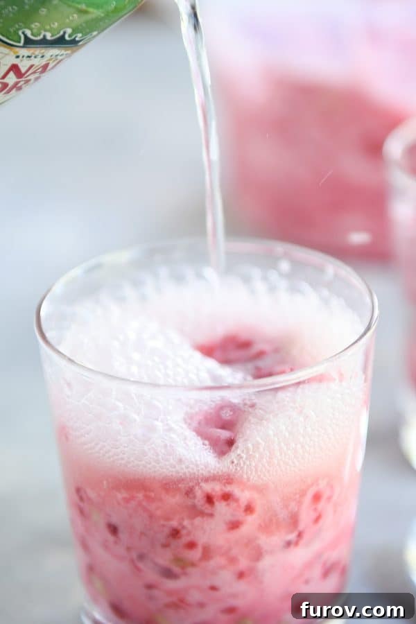 Pink Paradise Sorbet 9 Pouring ginger ale into glass with frozen pink sorbet.