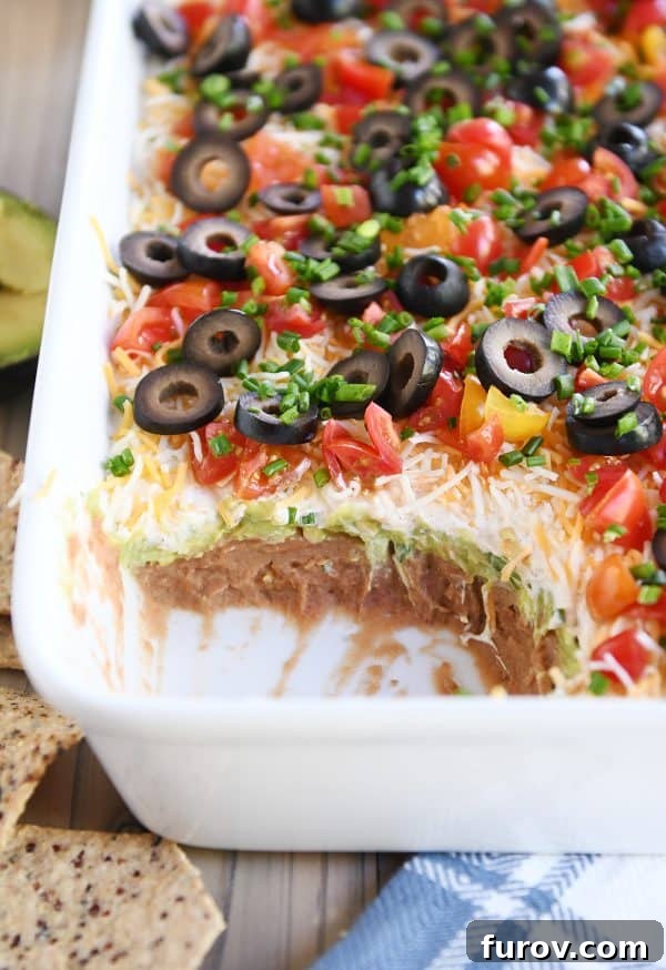 A scoop revealing all seven vibrant layers of a delicious 7-layer dip.