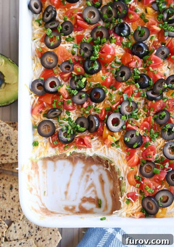 A top-down view of the easy 7-layer dip in a white casserole dish, showcasing its inviting texture and colors.