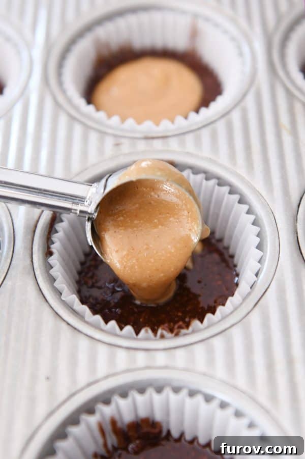Irresistible No-Bake Peanut Butter Cups: Vegan, Gluten-Free Indulgence 8 A hand scooping the peanut butter mixture onto the chocolate base in a muffin liner, illustrating the final assembly step.