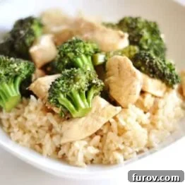 Simple Orange Chicken with Broccoli served in a white bowl over rice, garnished with fresh herbs.