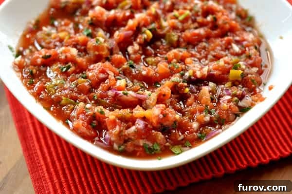 A crisp white bowl generously filled with a vibrant, chunky homemade salsa, ready for dipping.