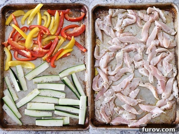 Fresh zucchini, vibrant bell peppers, and marinated chicken pieces are spread across two separate sheet pans, prepped for roasting.