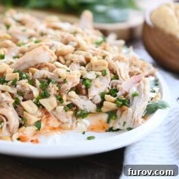 White platter with layered sesame Thai chicken dip, with a section scooped out