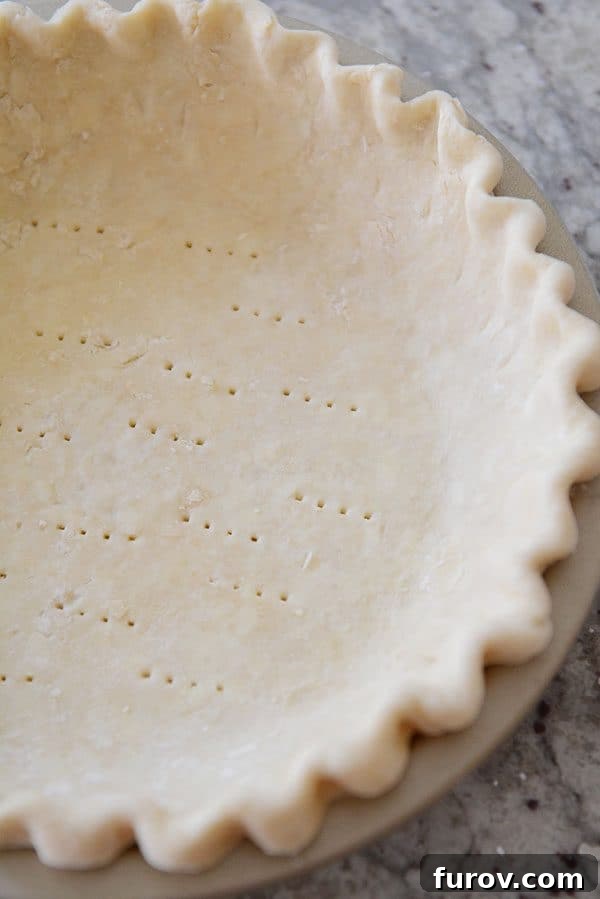 Unlock the Secret to Flaky Homemade Pie Crust 2 An uncooked crimped pie crust, showcasing its perfect form before baking.