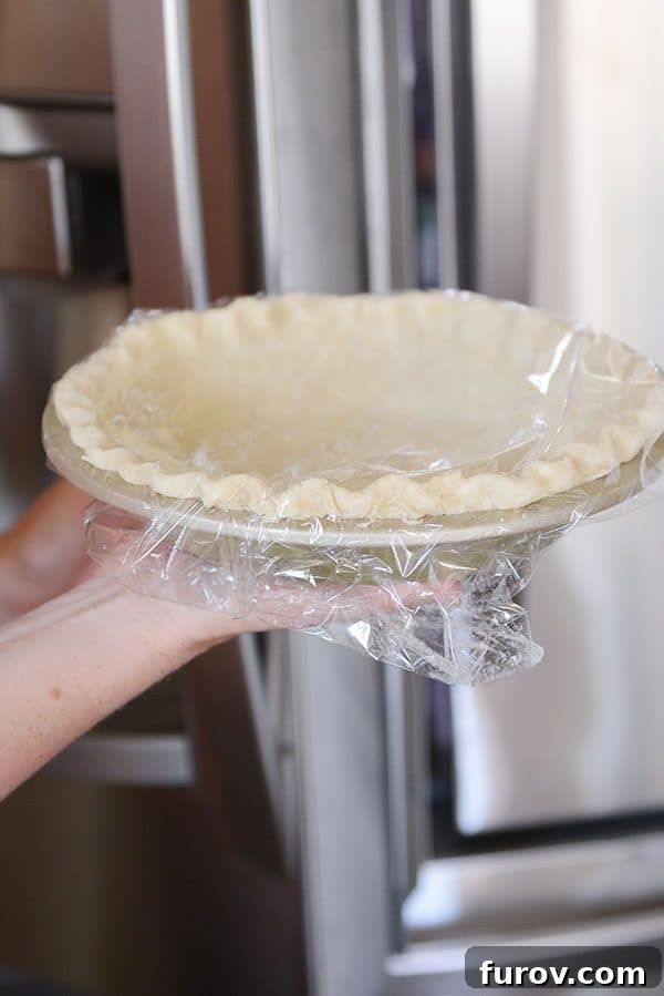 Unlock the Secret to Flaky Homemade Pie Crust 24 A pie crust, covered in saran wrap, being held, ready for its final chill.