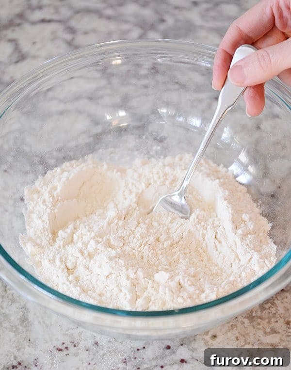 Unlock the Secret to Flaky Homemade Pie Crust 5 A fork stirring the dry ingredients in a glass bowl, ensuring they are evenly mixed.