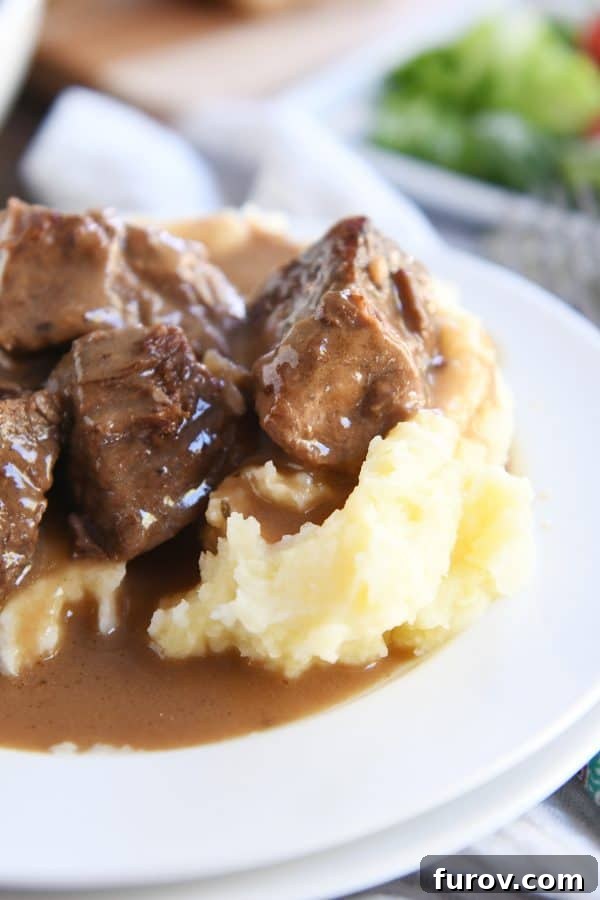 Fall-Apart Tender Slow Cooker Beef in Rich Gravy 10 Slow cooker smothered beef tips and gravy on mashed potatoes, garnished with fresh parsley.