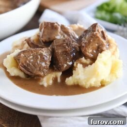 Smothered beef tips and mashed potatoes on a white plate