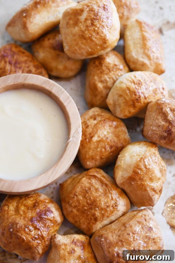 Sourdough for the Unmotivated 13 Easy homemade soft pretzel bites on sheet pan with bowl of cheese sauce.