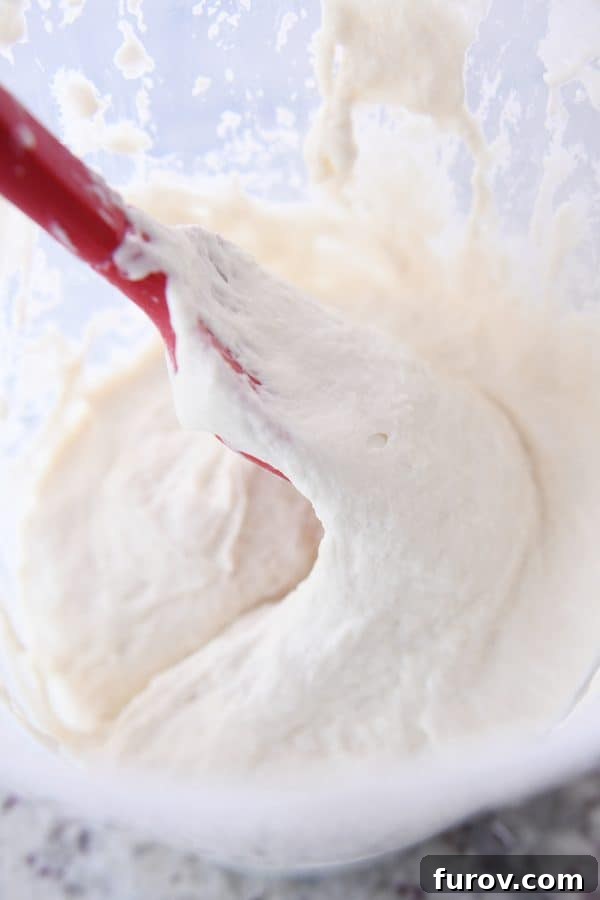 Sourdough for the Unmotivated 8 Stirring sourdough starter in bucket with red rubber spatula.