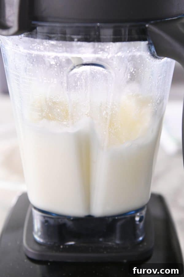 Hot water, butter, and eggs being blended together in a high-speed blender, creating a frothy mixture.