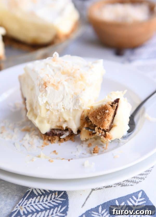 A delectable bite of Black Bottom Banana Coconut Cream Pie on a fork, resting on two stacked white plates.