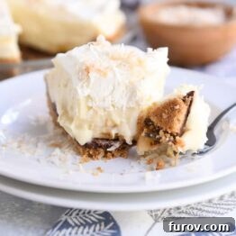 Bite taken out of Black Bottom Banana Coconut Cream Pie on white plate with fork