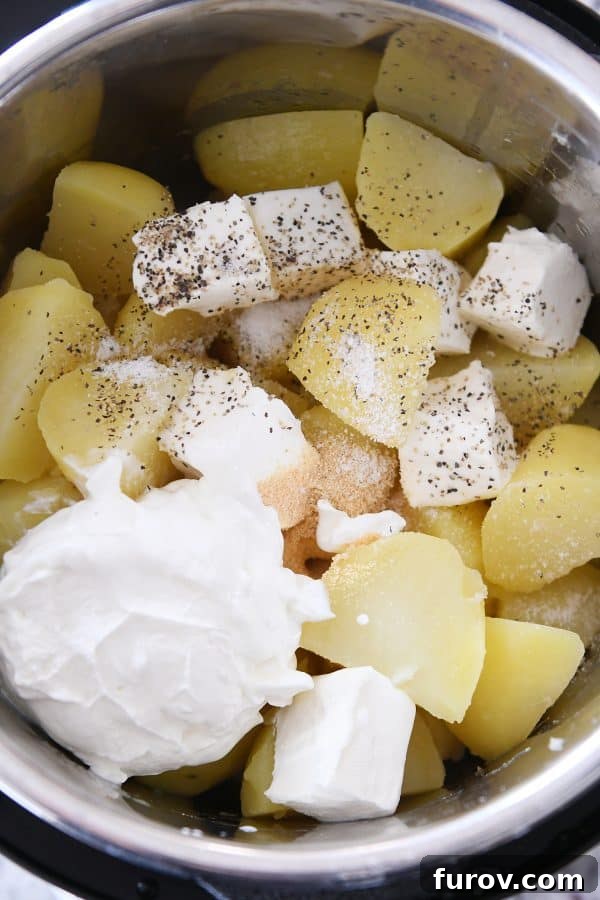 Instant pot of cooked potatoes, sour cream, butter, and cream cheese.